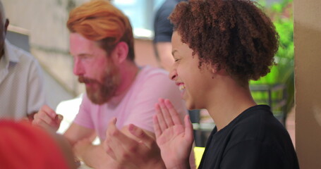 Hispanic Latin teenager of African descent laughing joyfully while engaging with others during a lively outdoor family meal, capturing energy and connection
