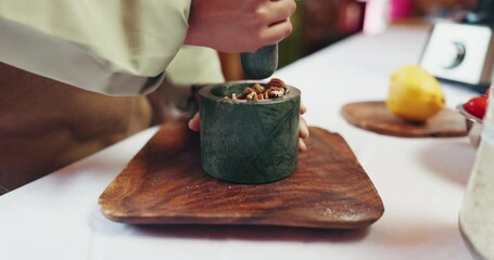 Hands, woman and grind nuts in mortar for cooking flavor, meal preparation or dinner process. Chef, home baking and person blend ingredients for food recipe, culinary skills or pastry dish in kitchen