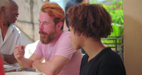 Hispanic Latin teenager of African descent laughing joyfully while engaging with others during a lively outdoor family meal, capturing energy and connection