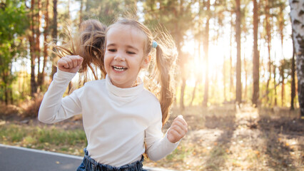 Happy child girl having fun walking a park on a sunset