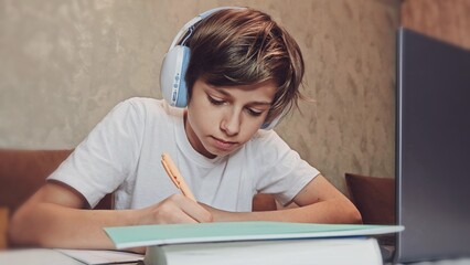 Boy Uses Laptop for Learning, Writes Down Useful Information. Distance Learning, e-Education, Homeschooling Concept. Portrait of a Boy Doing Homework
