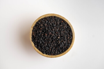 black sesame in a wooden bowl on a white background.