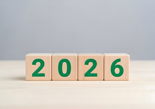 Four wooden blocks displaying the year two thousand twenty seven in green font on a light surface