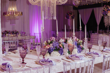 ELEGANT TABLE WITH A LARGE LAMP AND GLASSES AND PLATES WITH PURPLE FLOWERS