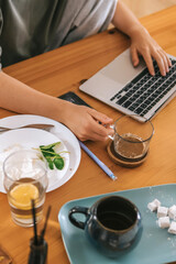  Gen Z woman working from home at cozy kitchen table with laptop and phone. Digital nomad lifestyle, mindfulness, remote work, balance, mental calm and modern freelancing