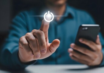 A person pressing a glowing power button while holding a smartphone in their other hand close up view