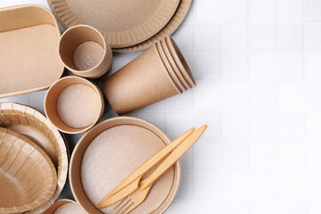 Set of disposable tableware on white tiled table, flat lay. Space for text