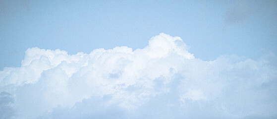 Vintage grainy film captures beautiful clouds against a clear blue sky.