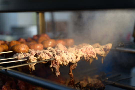 Grill with skewers and sausages, cooking over open flames. Gnummareddi or torcinelli, rolls based on lamb offal (liver, lung and kidney), italian food specialty typical of Southern Italy, Apulia