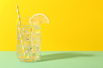 Refreshing water with ice and lemon on color background. Space for text