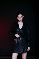 A young woman model in a dress in a photo studio on a black background with red light