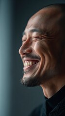 Obraz premium Gleeful Gaze: A candid portrait capturing the unfiltered joy of an Asian man as he closes his eyes in a moment of genuine laughter, showcasing his expressive smile and emotional depth.