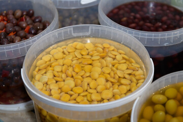 Lupini beans in brine. Pickled lupin in plastic container at evening street market in Italy