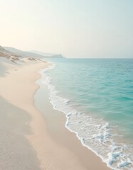 Photo shows stunning coastline. Soft white sand meets turquoise ocean under clear sky. Peaceful beach scenery evokes feelings of calm relaxation on vacation