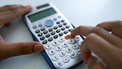 Hands Using Scientific Calculator on White Surface, Close-up of hands using a scientific calculator on a white surface - Powered by Adobe