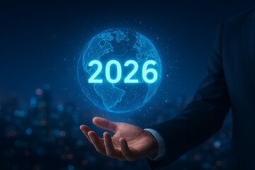 A businessman holds a glowing globe with the number 2026 symbolizing global business, world connectivity, and technological advancement into the new year with success