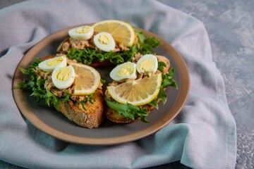 Bruschetta with cod liver, quail eggs, lemon and herbs. Italian Cuisine. Healthy eating.