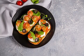 Bruschetta with cherry tomatoes, mozzarella cheese, olives and herbs. Italian Cuisine. Healthy eating.