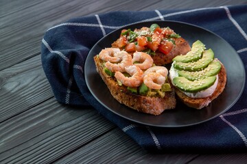 Bruschetta with avocado, shrimp, tomatoes, guacamole, cream cheese and herbs. Healthy eating.