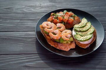 Bruschetta with avocado, shrimp, tomatoes, guacamole, cream cheese and herbs. Healthy eating.