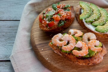 Bruschetta with avocado, shrimp, tomatoes, guacamole, cream cheese and herbs. Healthy eating.