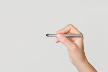 Person's hand holding a stylus pen ready to write or draw on a screen