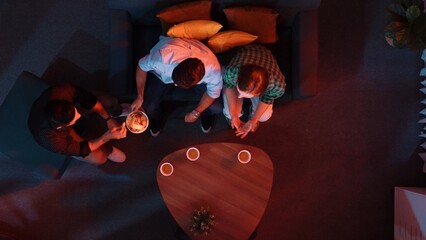 Top aerial view of caucasian father and mother watching movie while eating snack with friend. Happy...