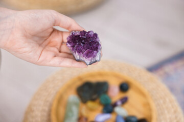 Woman with beautiful amethyst gemstone and other mineral stones indoors, closeup. Space for text