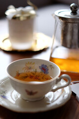 Tea time in vintage porcelain cup with glass teapot and a candle in the background. Close-up of a...