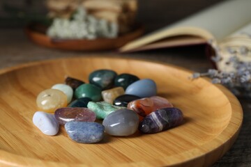 Different beautiful gemstones, lavender flowers and book on table, closeup