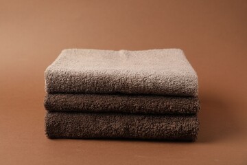 Stack of fresh terry towels on brown background
