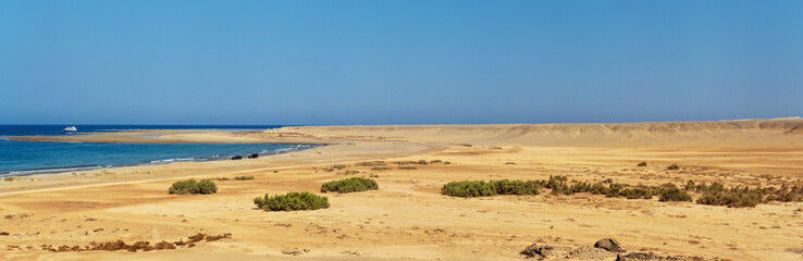 Desert beach landscape near Marsa Mubarak in Egypt, few cars parked on the shore, wide panorama