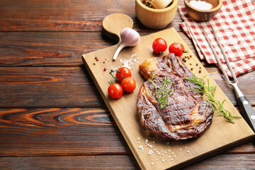 Delicious grilled beef steak with herbs, spices and products on wooden table, closeup. Space for text