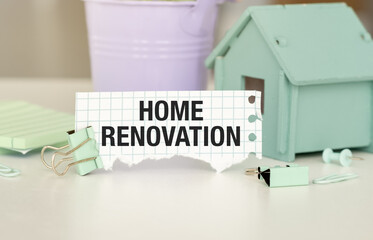 A sign that says Home Renovation is on a table. There are also some hose and a potted plant in the background