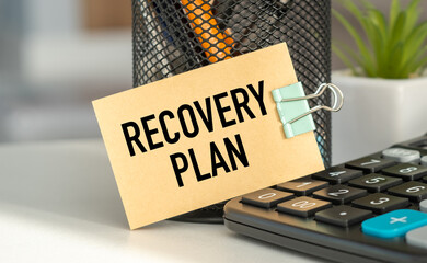 A clipboard with a sign that says Recovery Plan is on top of a calculator.