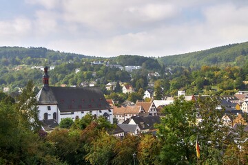 European village with church and houses on hills in green valley.