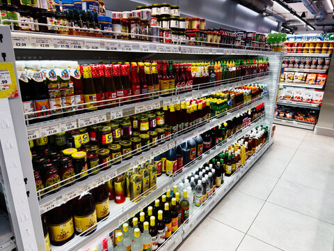 Aisle of sauces and condiments stocked on bright supermarket shelves in a busy grocery store