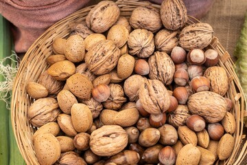 A close-up of a basket full of fresh almonds, hazelnuts and walnuts, overflowing with abundance for healthy eating and well-being.