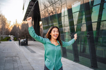 Businesswoman celebrating success outside office building