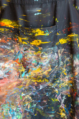 Colourful paint splashes over artist apron closeup