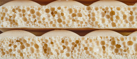 Macro close-up of aerated caramel chocolate bars in two stacked rows. Sweet porous texture with airy bubbles, perfect for dessert branding, packaging, and gourmet confectionery design. Banner