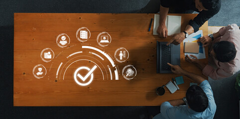 Aerial view of a collaborative team working on project management, enhanced by digital icons that symbolize success and strategic planning in a modern office environment. Trope