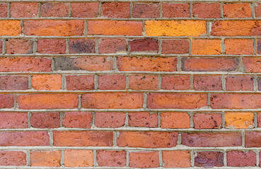 Red, brown background of uneven brickwork with lines of cement joints. Close-up multi-colored texture.