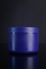 Jar of hair care cosmetic product for blonde hair on dark background