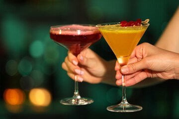Friends clinking glasses with cocktails in bar, closeup