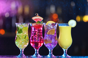 Glasses of alcoholic cocktails with garnish on table against blurred background