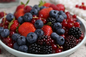 Different ripe berries on light grey textured table, closeup