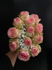 Person holding bouquet of pink roses