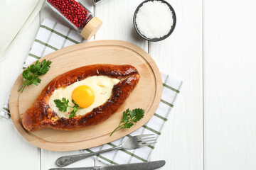 Tasty khachapuri with cheese and egg served on white wooden table, flat lay. Space for text