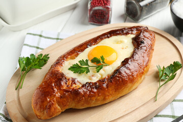 Tasty khachapuri with cheese, egg and spices on white wooden table, closeup